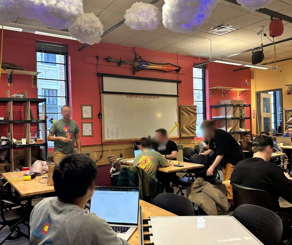 A group of people sitting at desks in the Atlas Institute classroom at CU Boulder.