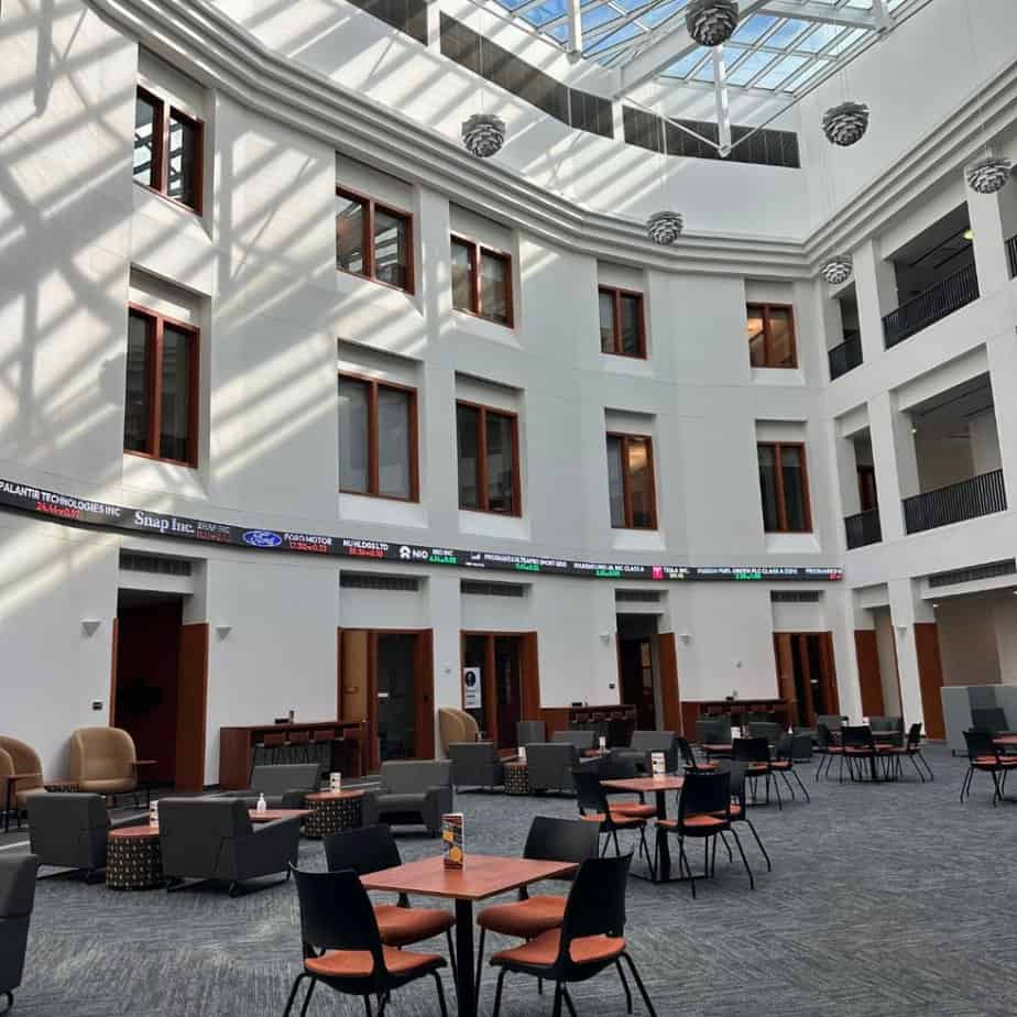 The lobby of a large building at the University of Wyoming with tables and chairs, showcasing its unique charm.